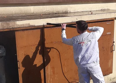 Radnik u radnoj odjeći Adriacolor pere metalna vrata visokotlačnom pumpom.