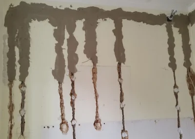 Zid sa saniranim utorima od elektroinstalacija prekrivenim svježim mortom.